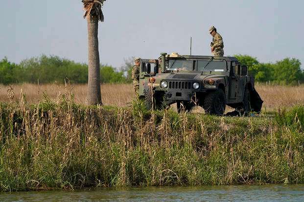 Members of the National Guard stand near a vehicle along the U.S.-Mexico border in Mission, Texas.