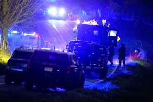 Law enforcement officers, right, stand near armored and tactical vehicles