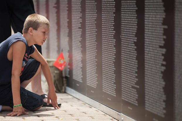 Hunter Mora, grandson of Marine Vietnam War veteran Donald Mora, looks for the names of his granddad's fallen comrades from the war at the traveling Vietnam War Memorial Wall in Voinovich Park in Cleveland, June 12, 2012. (Cpl. Chelsea Anderson/U.S. Marine Corps photo)