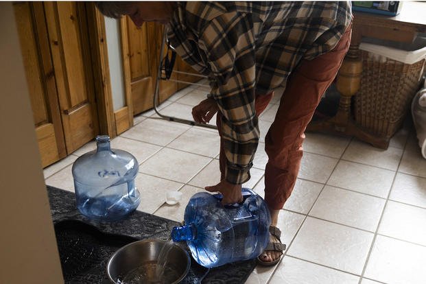 Using water provided by the Air Force, Marcie Zambryski fills bowls up for her boxers, Livie and Louie. Her home is near Deep Creek, 8 miles away from Fairchild Air Force Base.