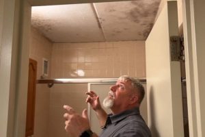 A lead mold remediation specialist at Fort Stewart shows where a barrack room's bathroom ceiling has mold.