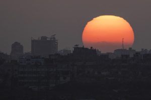 The sun sets behind the buildings in the Gaza Strip.