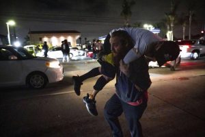 A person carries an injured protester to cover during a protest in Compton, California.