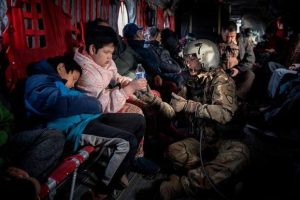 Alaska Army National member passes a bottle of water to a child.