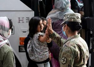 Army soldier gives a high five to a small child from Afghanistan.